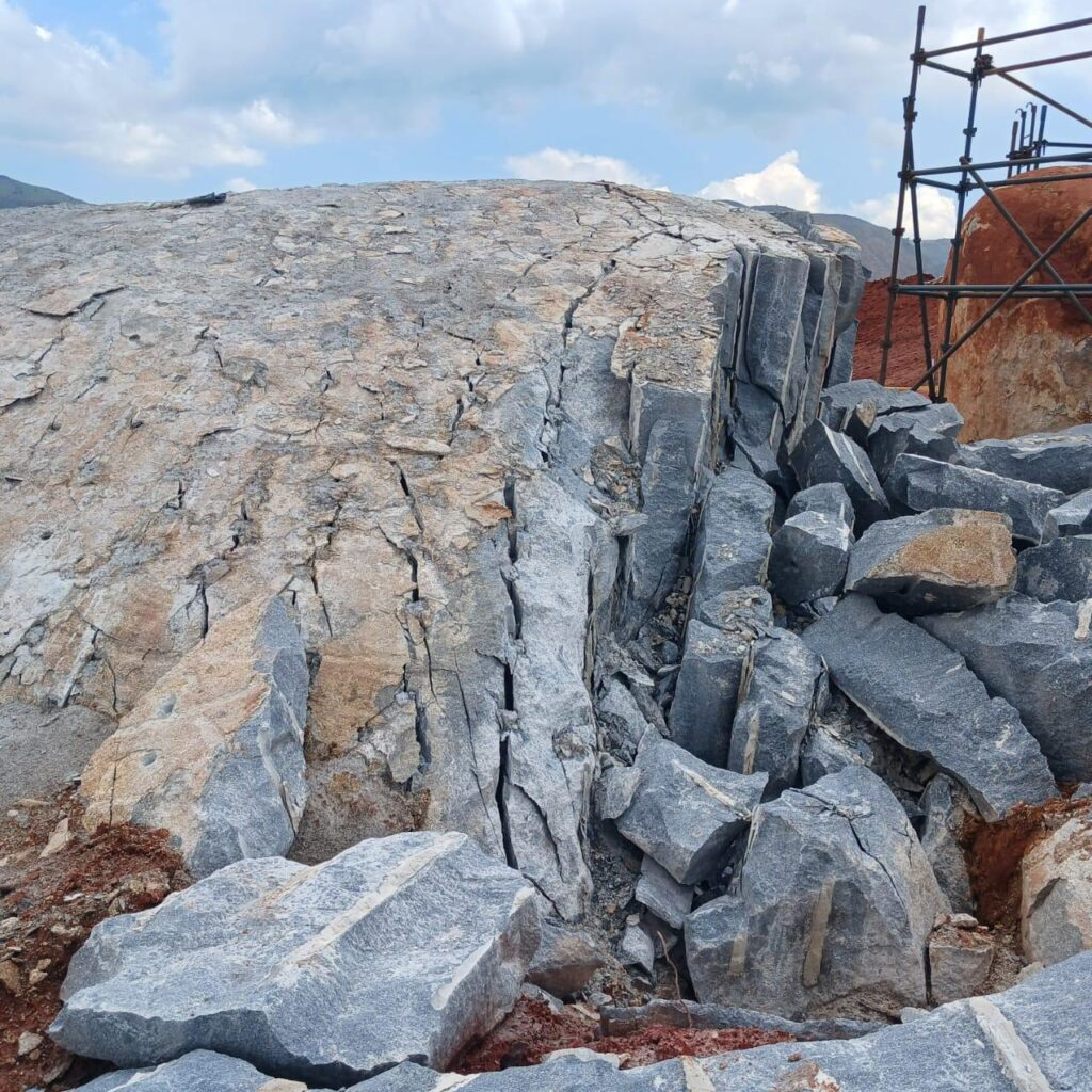 Drilling and pouring of Rock breaking Chemical on massive out crop of rock on a mine.